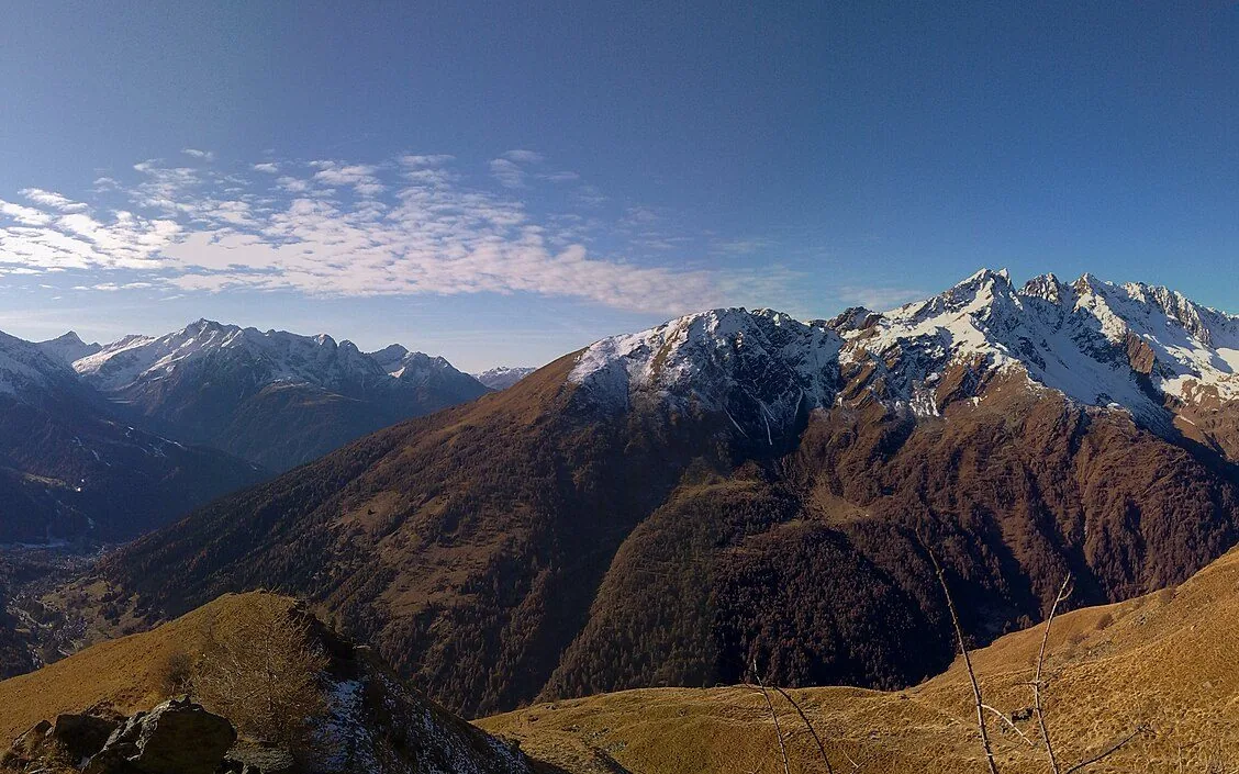 Pendii dorati in autunno e cime spruzzate di neve sopra la Valle di Viso